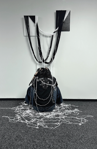 Megan Fang's 2025 winning conceptual artwork with a seated figure covered in black and white threads.